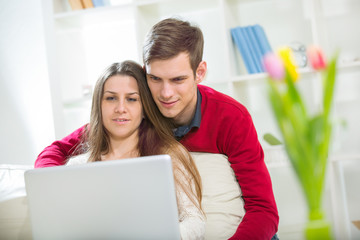 Young couple relaxing on sofa with laptop in the living room.Sel