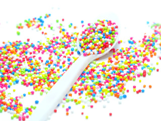 colorful sugar pearls in white spoon
