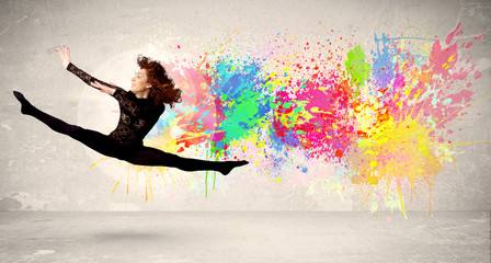 Fototapeta na wymiar Happy teenager jumping with colorful ink splatter on urban backg