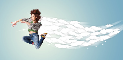 Healthy young woman jumping with feathers around her