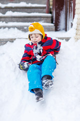kid boy in colorful clothes having fun with riding on snow, outd