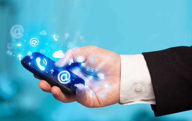 Business man holding smart phone with media icons