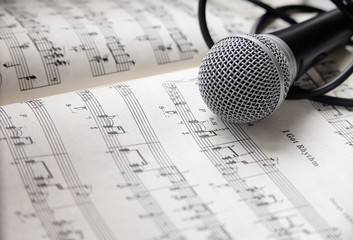 Microphone and cable lying on sheet of music
