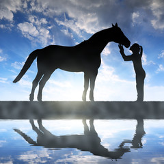 Silhouette of a girl giving a kiss horse in sunset