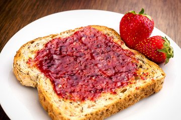 Macro closeup of delicious strawberry jam on whole wheat toast