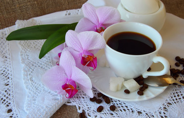 Cup of coffee and a branch of orchid.