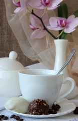 A cup of coffee, candy and branch orchid.