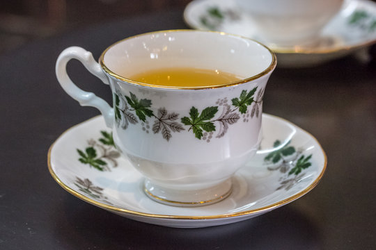 White tea cup stands on a black saucer.