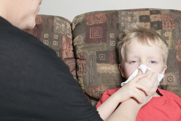 Single mother with son who suffers from a cold. She is helping h