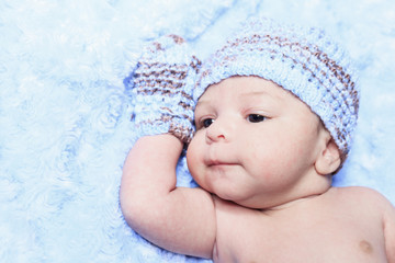 A Closeup of the face of a tiny, newborn baby boy wearing a blue