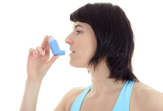 Close up image of a young woman using inhaler for asthma. White