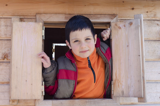 Child Boy Playing In Wooden Playhouse, Looking From Open Window