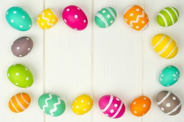 Colorful Easter egg frame against white wood