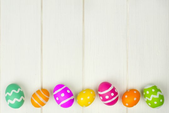 Colorful Easter egg bottom border against white wood