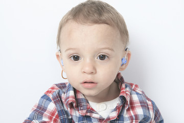A boy with a hearing aids on gray background