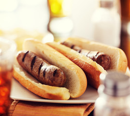 two juicey bratwursts on plate in hot dog buns