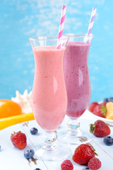 Delicious berry cocktails on table on water background