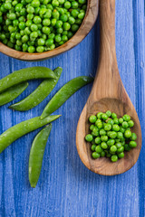 wooden spoon with fresh peas and whole beans on rustic table