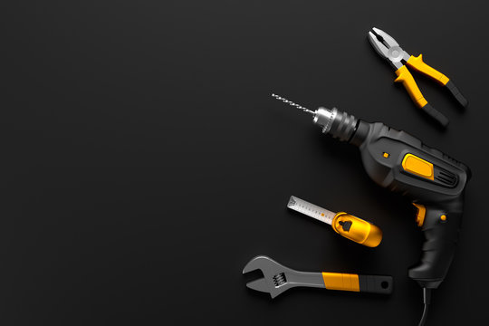 drill, wrench and construction tools on the black background tex