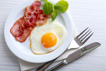 Bacon and eggs on color wooden table background