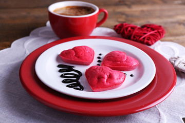 Cookies in form of heart in plate with cup of coffee