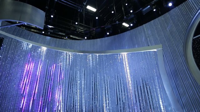 Tilt up from shiny beaded curtain to lights on stage