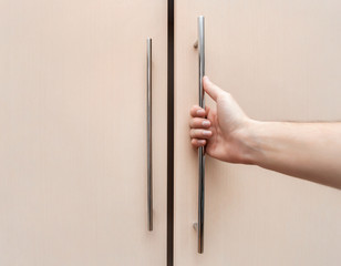 male hand are open the cupboard doors, light wood