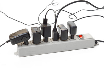 Many plugs and adapters plugged into electric power bar