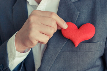 Businessman pulling out a red heart from the pocket of his suit