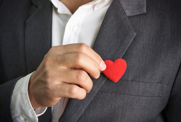 Businessman pulling out a red heart from the pocket of his suit