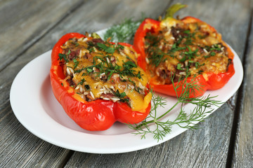 Stuffed red peppers with greens on plate on wooden table