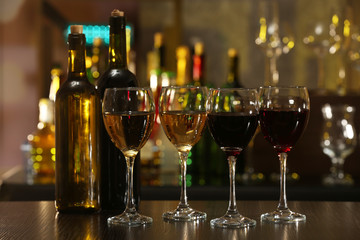 Glasses of wine on counter and bar on background