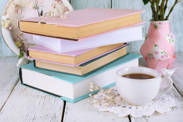 Cup of tea with books and clock on wooden background