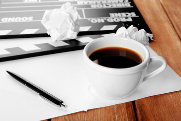 Movie clapper with paper, pen and cup of coffee