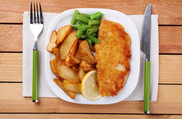 Breaded fried fish fillet and potatoes with asparagus and lemon