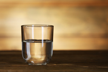 Glass of clean mineral water on rustic wooden background