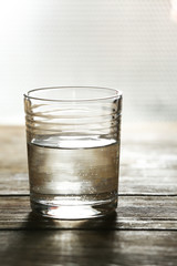 Glass of clean mineral water on surface and background