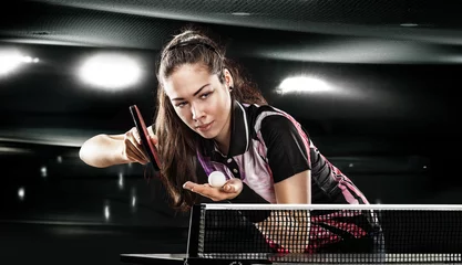 Fotobehang Young pretty sporty girl playing table tennis on black © Mike Orlov
