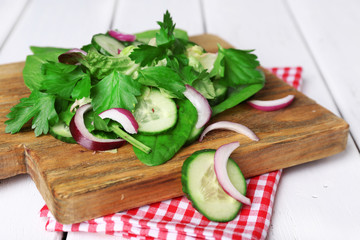 Mix salad leaves with sliced cucumber and onion