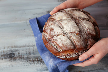 Loaf of freshly bread in female hands with napkin
