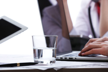 Working with laptop at worktable on white blurred background