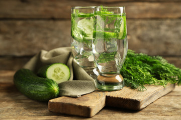 Glasses with fresh organic cucumber water on wooden table