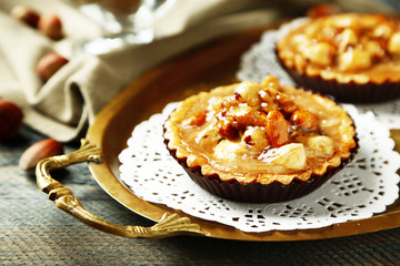 Mini cakes with nuts on napkin on wooden background