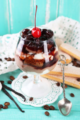 Tasty tiramisu dessert in glass, on color wooden background