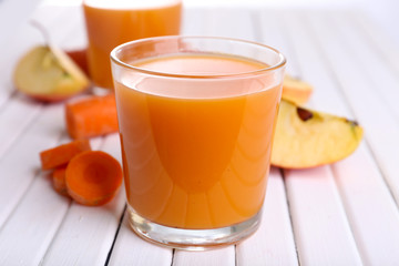 Glasses of juice with apple and carrot on wooden table close up