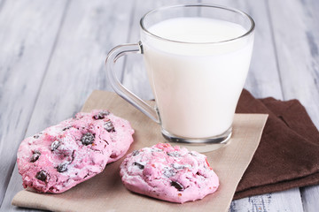 Pink cookies and cup with milk on table close-up