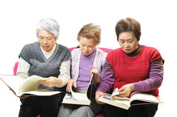 Fototapeta premium 分厚い本を読んで勉強している高齢者のおばあさん3人組