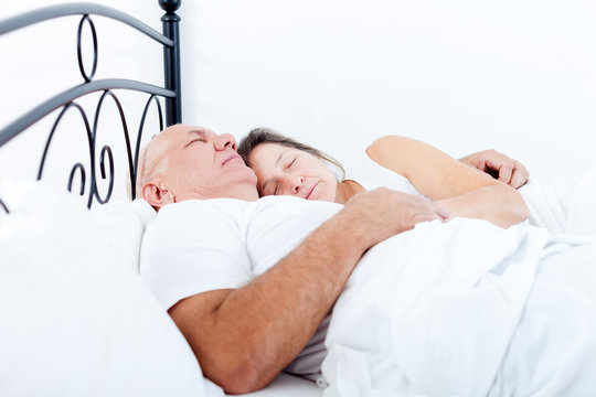 elderly couple sleeping in bed.