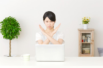 パソコンの前でバツ印する女性