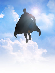 Silhouette of a superhero figure flying on clouds © rudall30